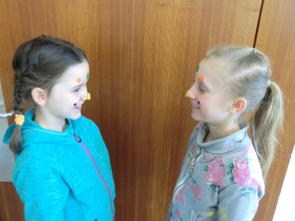 Zwei Schülerinnen stehen sich gegenüber. Sie haben Klebepunkte im Gesicht.