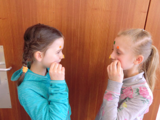 Zwei Schülerinnen kleben sich Klebepunkte ins Gesicht