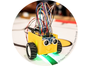 ein Roboter mit einem gelbem Gehäuse, zwei Rädern und abstehenden bunten Kabeln