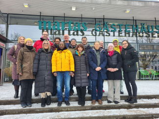 Gruppenbild des BackStage Teams: 15 Personen stehen auf einer Treppe vor einem Gebäude.