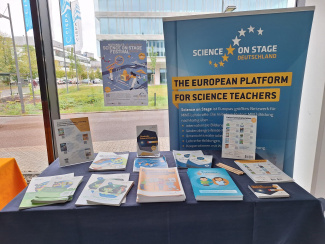 Ein Stand mit Flyern und Broschüren von Science on Stage, im Hintergrund steht ein Banner
