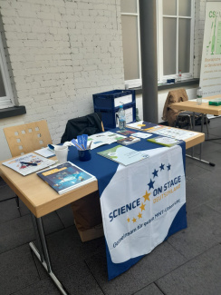ein Informationsstand, auf dem Tisch liegt eine Tischdecke mit der Aufschrift: Science on Stage