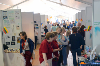 Viele Menschen stehen vor verschiedenen Messeständen in einem Veranstaltungszelt.