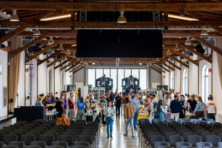 Blick auf einen bestuhlten Veranstaltungssaal mit zwei Lokomotiven im Hintergrund