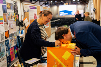 Ein Mann beugt sich an einem Ausstellungsstand über einen von innen beleuchteten Kasten