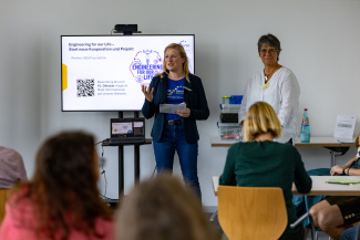 Zwei Referentinnen vor einer Leinwand in einem Seminarraum