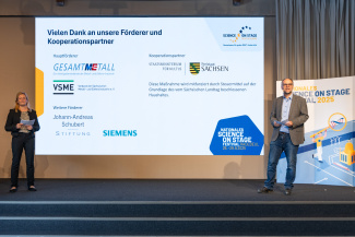 Zwei Moderatoren vor einer Leinwand mit Dank an die Förderer des Science on Stage Festivals
