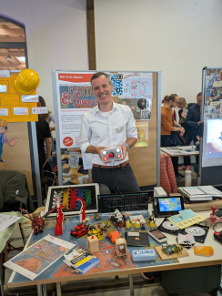 Ein Aussteller an einem Messestand mit bunten Ausstellungsobjekten