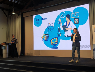 Eine Rednerin vor einem großen Schaubild auf einer Leinwand