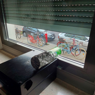 eine Lochkamera liegt drinnen an einem Fenster mit halb geschlossenen Rolläden