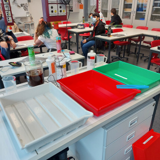 eine weiße, eine rote und eine grüne Wanne liegen auf dem Tisch im Chemieraum