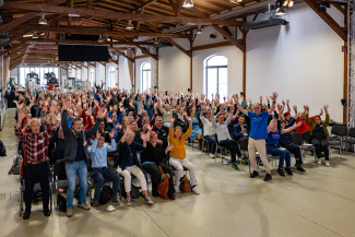 Ein voll besetzter Veranstaltungssaal, die Zuhörer recken jubelnd die Arme in die Luft