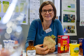 Eine Ausstellerin mit einer Zuckerrübe an einem Stand der Bildungsmesse