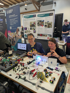 Zwei Aussteller führen Experimente mit Klemmbausteinen an einem Messestand vor
