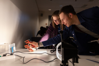 zwei Personen beugen sich über ein Experiment mit Licht