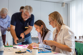 Drei Personen beugen sich bei einem Workshop über ein Experiment